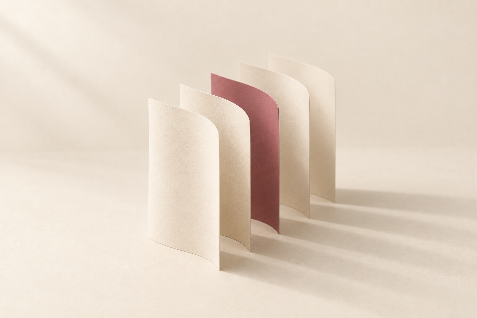 Five curved sheets of paper standing in a row, one rose
